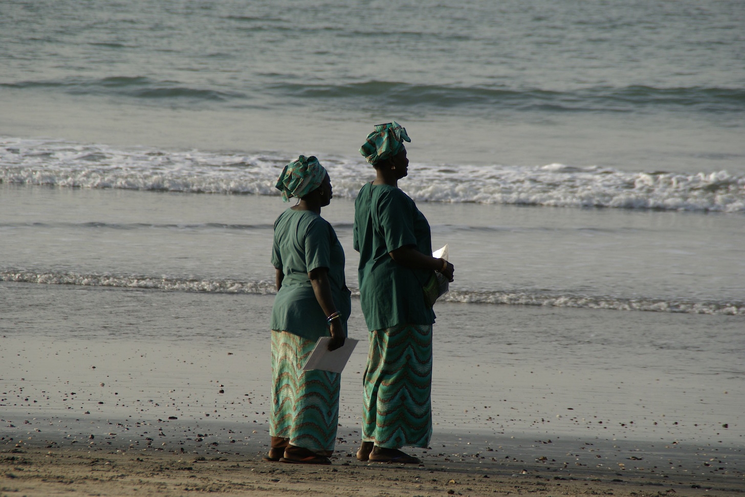 Two women stand on the beach in the Gambia. 